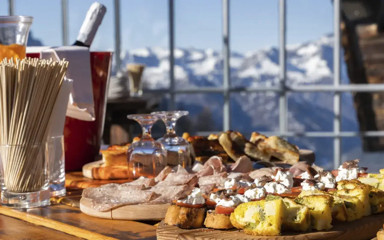 Buffet di stuzzichini con salumi, bruschette e frittata, con vista sulle montagne innevate. Un'esperienza soft all inclusive.