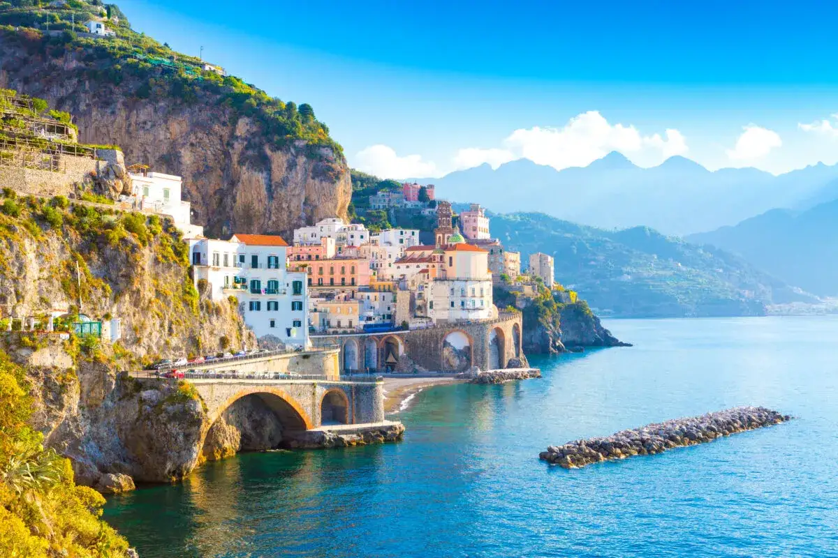 Costiera Amalfitana: case colorate aggrappate alla roccia, archi imponenti e mare blu. Un'immagine perfetta per il marketing turistico.